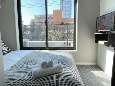 a bedroom with two towels on a bed with a large window at COMMA HOUSE Shinjuku 401 in Tokyo