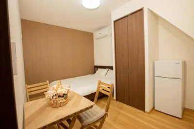 a room with a bed and a table and a refrigerator at \u30a2\u30f3\u30c9\u30b9\u30c6\u30a4\u6d45\u83495\u4e01\u76ee1f in Tokyo
