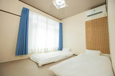a bedroom with two beds and a window at \u30a2\u30f3\u30c9\u30b9\u30c6\u30a4\u6d45\u83495\u4e01\u76ee2f in Tokyo