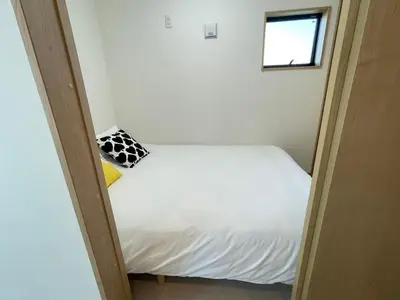 a small bedroom with a white bed and a window at COMMA HOUSE Kitaikebukuro 303 in Tokyo