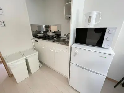 a small kitchen with a white refrigerator and a sink at COMMA HOUSE Kitaikebukuro 303 in Tokyo