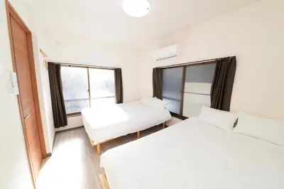 two beds in a room with two windows at \u548c\u30ce\u6953cottage\u7b2c\u4e09 \u65b0\u5bbf\u306e2\u968e\u5efa\u30664\u5ba42\u30b7\u30e3\u30ef\u30fc2\u30c8\u30a4\u30ec in Tokyo
