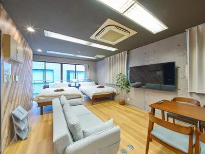 a large room with two beds and a tv at Shimbashi Hotel Sho in Tokyo