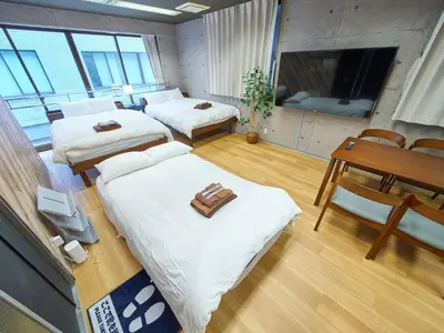a room with two beds and a table and a television at Shimbashi Hotel Sho in Tokyo