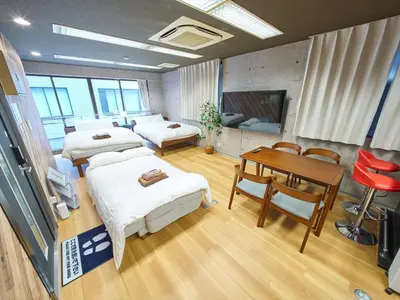 a room with two beds and a table and a television at Shimbashi Hotel Sho in Tokyo