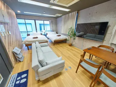 a room with two beds and a couch and a table at Shimbashi Hotel Sho in Tokyo
