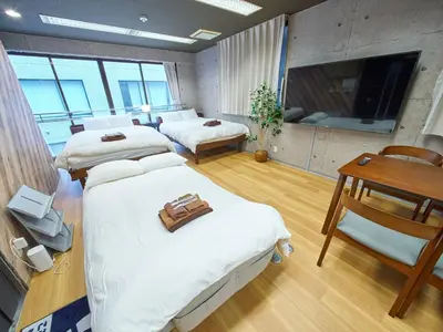 a room with three beds and a table and a television at Shimbashi Hotel Sho in Tokyo