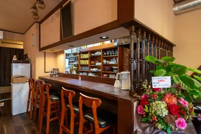 a bar in a restaurant with wooden chairs and flowers at \u30ed\u30fc\u30ba\u30d1\u30fc\u30af\u516b\u756a\u9928 in Tokyo
