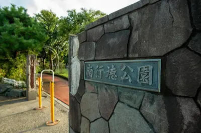 a sign on the side of a stone wall at \u30ed\u30fc\u30ba\u30d1\u30fc\u30af\u516b\u756a\u9928 in Tokyo
