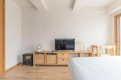 a bedroom with a television on a wooden dresser at Ken Hotel Tokyo Shinjuku in Tokyo