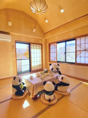 three panda bears sitting around a table in a room at \u6c11\u5bbf\u521d\u661f in Tokyo