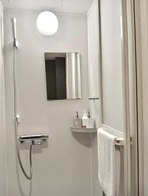 a white bathroom with a shower and a mirror at Remon House Asakusa Tokyo in Tokyo