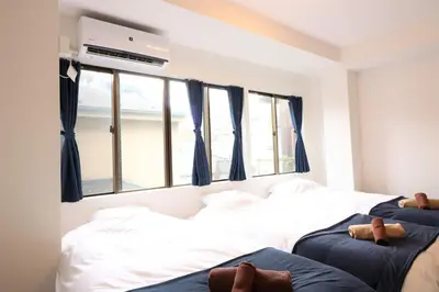 two beds in a room with blue curtains at Nishigokencho NA3 in Tokyo