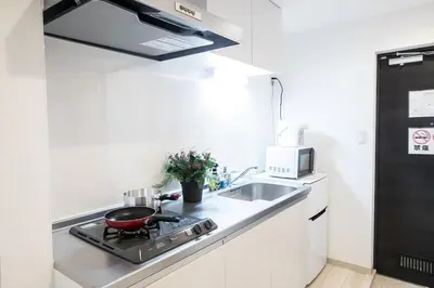 a small kitchen with a stove and a sink at COMMA HOUSE Nishi-Ikebukuro 11 in Tokyo