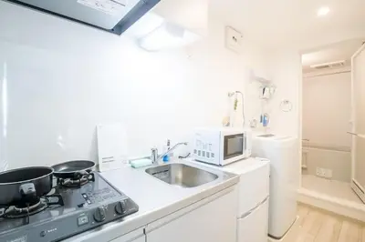 a kitchen with a stove and a sink and a microwave at COMMA HOUSE Nishi-Ikebukuro 2 UNITS 2131 in Tokyo