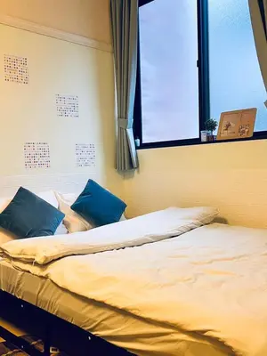 a bed with blue pillows in a room with a window at Shinjuku Suginami in Tokyo