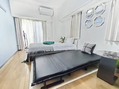 a bedroom with two beds and a bench in it at GM35\u65b0\u5bbf\u4e2d\u5fc3 \u8d85\u7ea7\u5546\u5708 \u4ea4\u901a\u67a2\u7ebd \u8f66\u7ad98\u5206\u949f \u6700\u59273\u4eba Shinjuku center 8 mins to ST 3P Maxs \u76f4\u8fbe\u65b0\u5bbf \u6d89\u8c37 \u8868\u53c2\u9053 \u54c1\u5ddd \u6c60\u888b \u4e0a\u91ce \u4ee3\u4ee3\u6728 \u94f6\u5ea7 \u539f\u5bbf in Tokyo