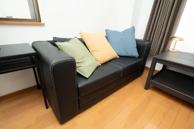 a black leather couch with pillows on it in a room at XS14 XROSS STAY Higashi shinjuku1 \u6771\u65b0\u5bbf in Tokyo