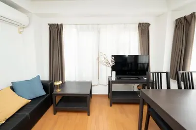 a living room with a black couch and a tv at XS14 XROSS STAY Higashi shinjuku1 \u6771\u65b0\u5bbf in Tokyo