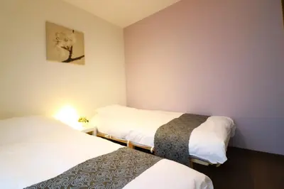 a room with two beds and a picture on the wall at Nishi Shinjuku House Five 1F HF1 in Tokyo