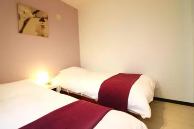 a room with two beds and a lamp on a table at Nishi Shinjuku House Five 1F HF1 in Tokyo