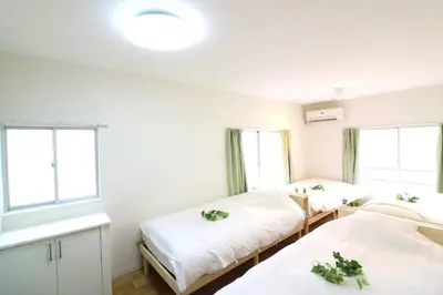 two beds in a room with two windows at Nishi Shinjuku House Five 2F HF2 in Tokyo