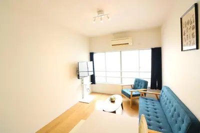 a living room with a blue couch and a table at Nishi Shinjuku House Five 2F HF2 in Tokyo