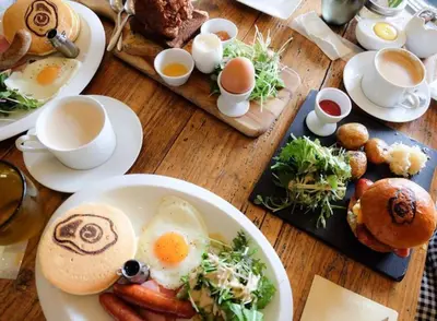 a wooden table with plates of breakfast foods and eggs at Nishi Shinjuku House Five 2F HF2 in Tokyo