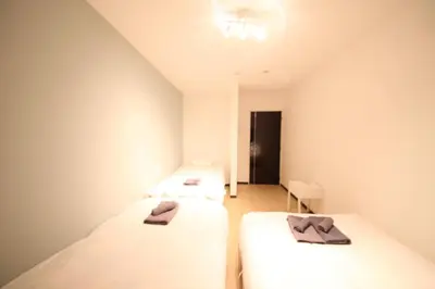 two beds in a small room with towels on them at Nishi Shinjuku House Five 2F HF2 in Tokyo