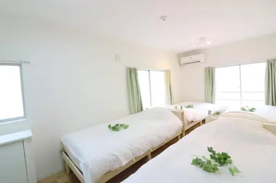 three beds in a room with windows at Nishi Shinjuku House Five 2F HF2 in Tokyo