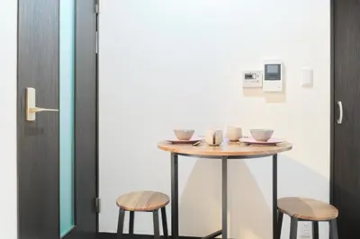 a small table with two stools next to a door at Marine Cove Hatsudai by Tranova in Tokyo