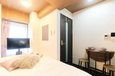 a bedroom with a bed and a table and a window at Marine Cove Hatsudai by Tranova in Tokyo