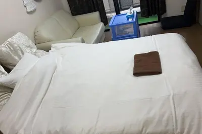 a white bed with a brown wallet on top of it at \u6574\u5957\u79c1\u4eba\u7a7a\u95f4 \u6674\u7a7a\u5854 \u89c2\u666f\u9633\u53f0 in Tokyo