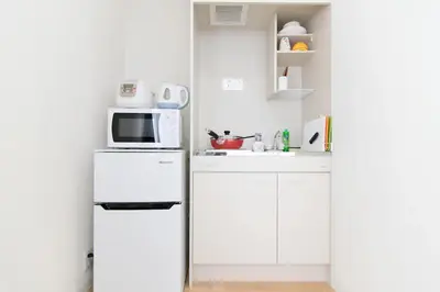a white kitchen with a microwave and a refrigerator at SY-HOTEL Kuramae 5mins \u673a\u573a\u76f4\u8fbe \u4ea4\u901a\u4fbf\u5229 \u8535\u524d5\u5206\u949f in Tokyo