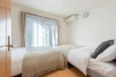 a bedroom with two beds and a window at \u5317\u6c60\u888b\u6238\u5efa in Tokyo