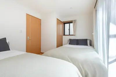 two beds in a white room with a window at \u5317\u6c60\u888b\u6238\u5efa in Tokyo