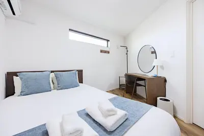 a white bedroom with a bed and a mirror at First Choice in Tokyo