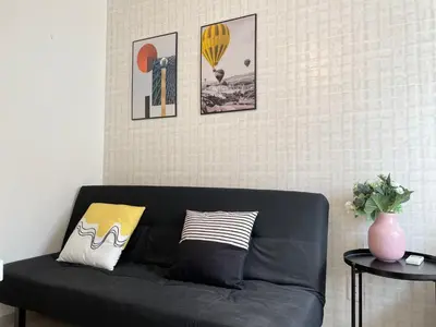 a black couch in a living room with pictures on the wall at COMMA HOUSE Nishi-Ikebukuro 3F in Tokyo