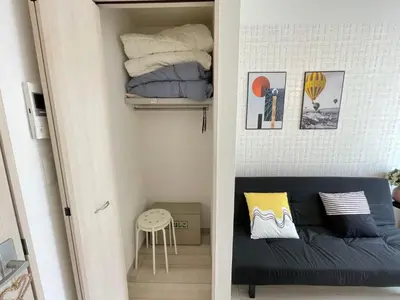 a small room with a couch and a stack of towels at COMMA HOUSE Nishi-Ikebukuro 3F in Tokyo