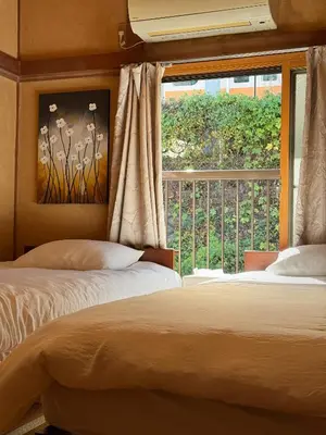 a bedroom with two beds and a large window at yoyogi house jellyne in Tokyo