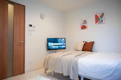 a bedroom with a bed and a tv on the wall at Craft202 \u6d45\u8349 \u30b9\u30ab\u30a4\u30c4\u30ea\u30fc\u8fd1\u304f \u6771\u4eac\u89b3\u5149\u306b\u6700\u9069 \u7a7a\u6e2f\u304b\u3089\u30a2\u30af\u30bb\u30b9\u826f\u597d \u7121\u6599WiFi in Tokyo