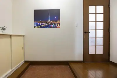 a room with a white wall with a picture on the wall at Tokyo Kitasen 4 in Tokyo