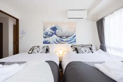 two beds in a room with a painting on the wall at Tokyo Kitasen 4 in Tokyo