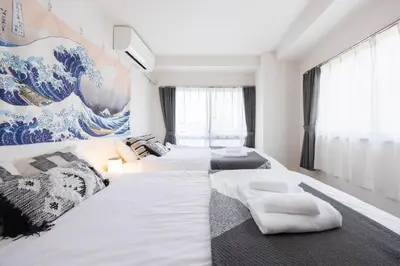 a bedroom with two beds and a painting of a wave at Tokyo Kitasen 4 in Tokyo