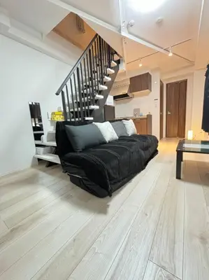 a black couch in a living room with a staircase at New\u6771\u4eac\u3067\u5bcc\u58eb\u5c71\u304c\u898b\u3048\u308bPentohouse ZEN \u5965\u6ca2\u99c51\u5206\u81ea\u7531\u30f6\u4e18\u5f92\u6b696\u5206\u6e0b\u8c37\u96fb\u8eca15\u5206 in Tokyo