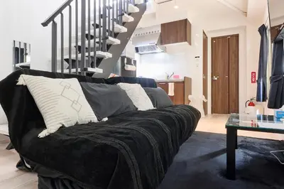 a living room with a black couch and stairs at New\u6771\u4eac\u3067\u5bcc\u58eb\u5c71\u304c\u898b\u3048\u308bPentohouse ZEN \u5965\u6ca2\u99c51\u5206\u81ea\u7531\u30f6\u4e18\u5f92\u6b696\u5206\u6e0b\u8c37\u96fb\u8eca15\u5206 in Tokyo