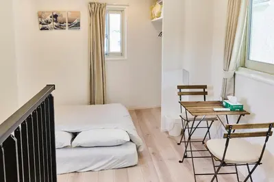 a room with a bed and a table and chairs at New\u6771\u4eac\u3067\u5bcc\u58eb\u5c71\u304c\u898b\u3048\u308bPentohouse ZEN \u5965\u6ca2\u99c51\u5206\u81ea\u7531\u30f6\u4e18\u5f92\u6b696\u5206\u6e0b\u8c37\u96fb\u8eca15\u5206 in Tokyo
