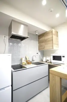 a kitchen with white appliances and wooden cabinets at GIVE Meidaimae in Tokyo