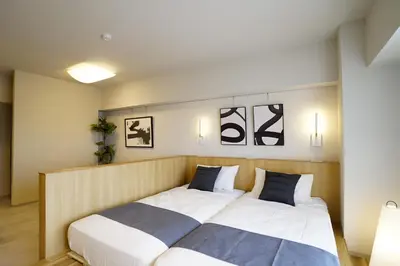 a bedroom with a bed with white and blue pillows at GIVE Meidaimae in Tokyo
