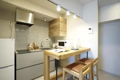 a kitchen with a wooden table and a microwave at GIVE Meidaimae in Tokyo